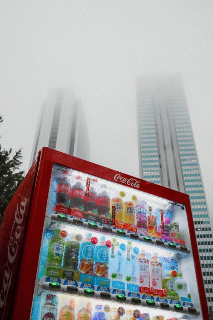 Photo of a Coca-Cola vending machine amidst foggy skyscrapers in Japan.